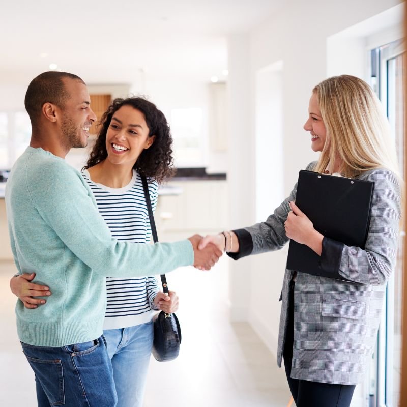 Real estate agent shaking hands with her clients