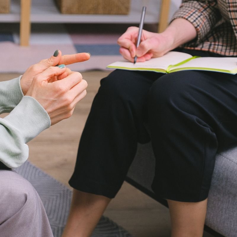 Close-up of therapist taking notes while sitting with patient